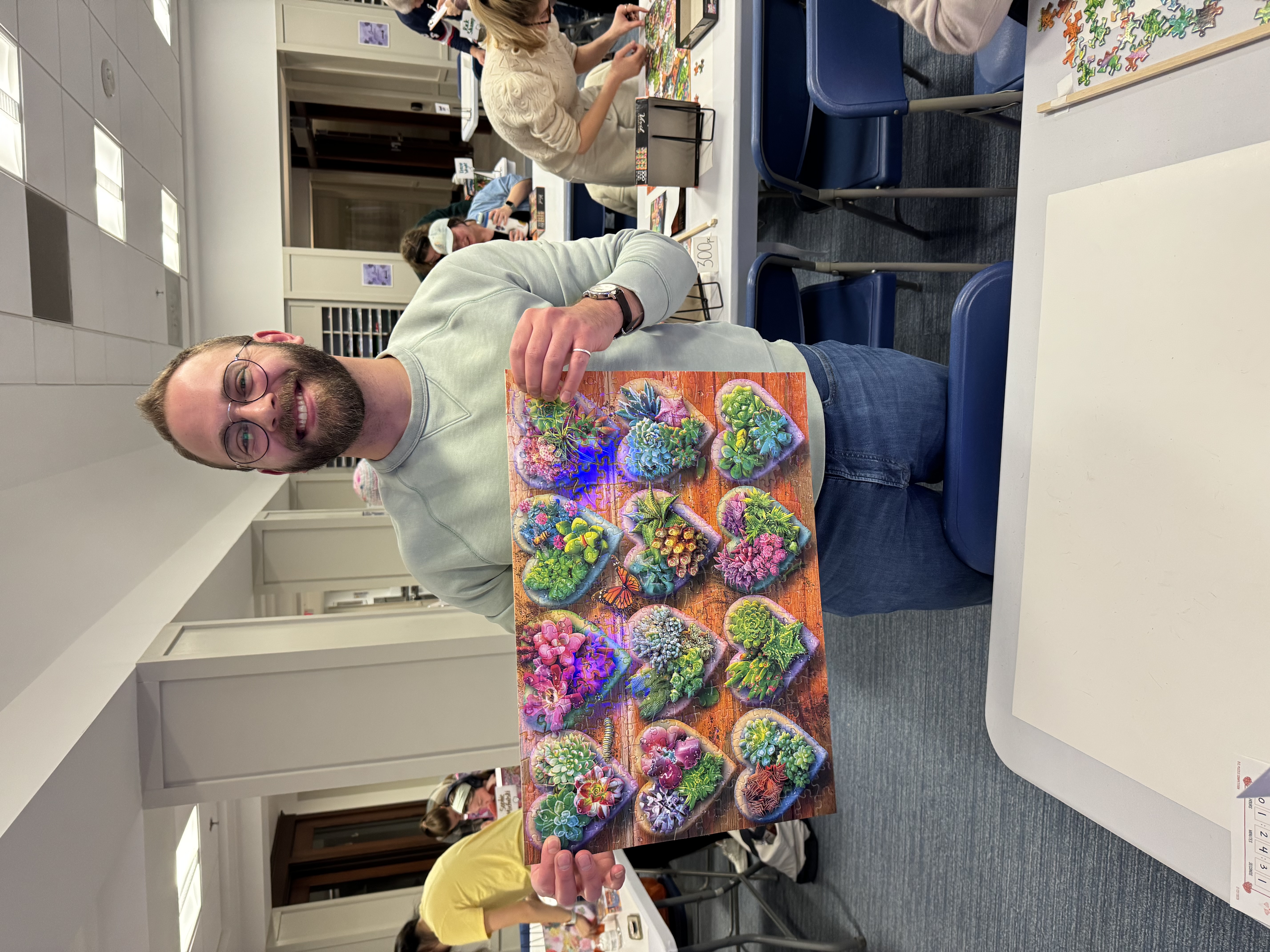 A photo of Andrew holding up my completed puzzle, Heart Succulents.
