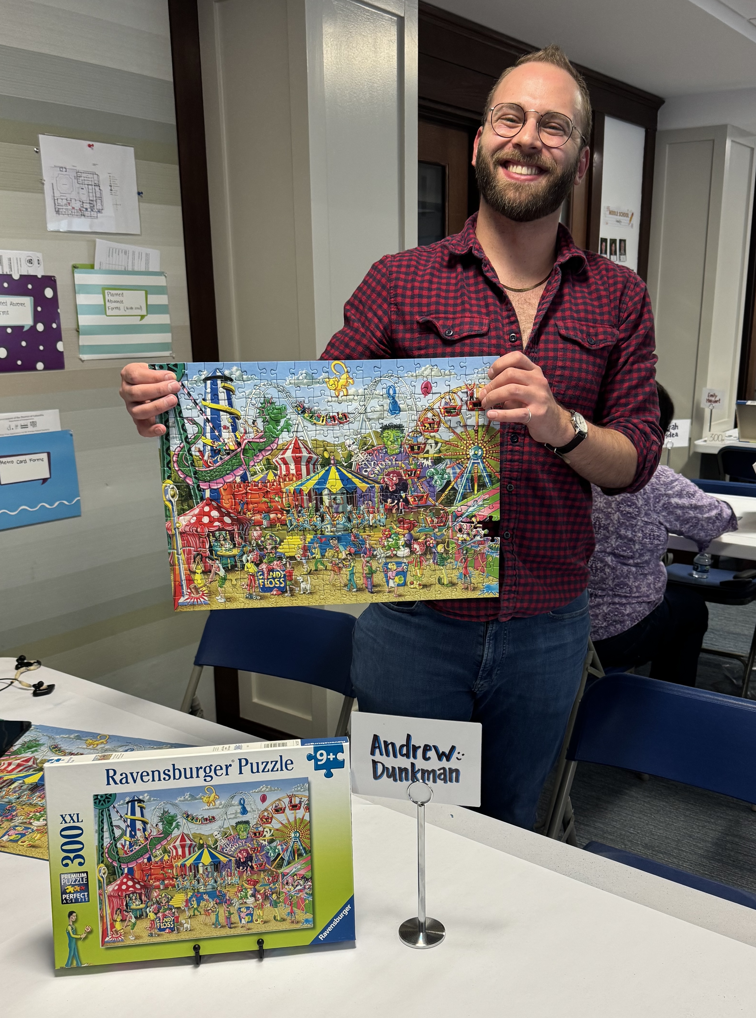 A photo of Andrew holding up my completed puzzle, Fun at the Carnival.