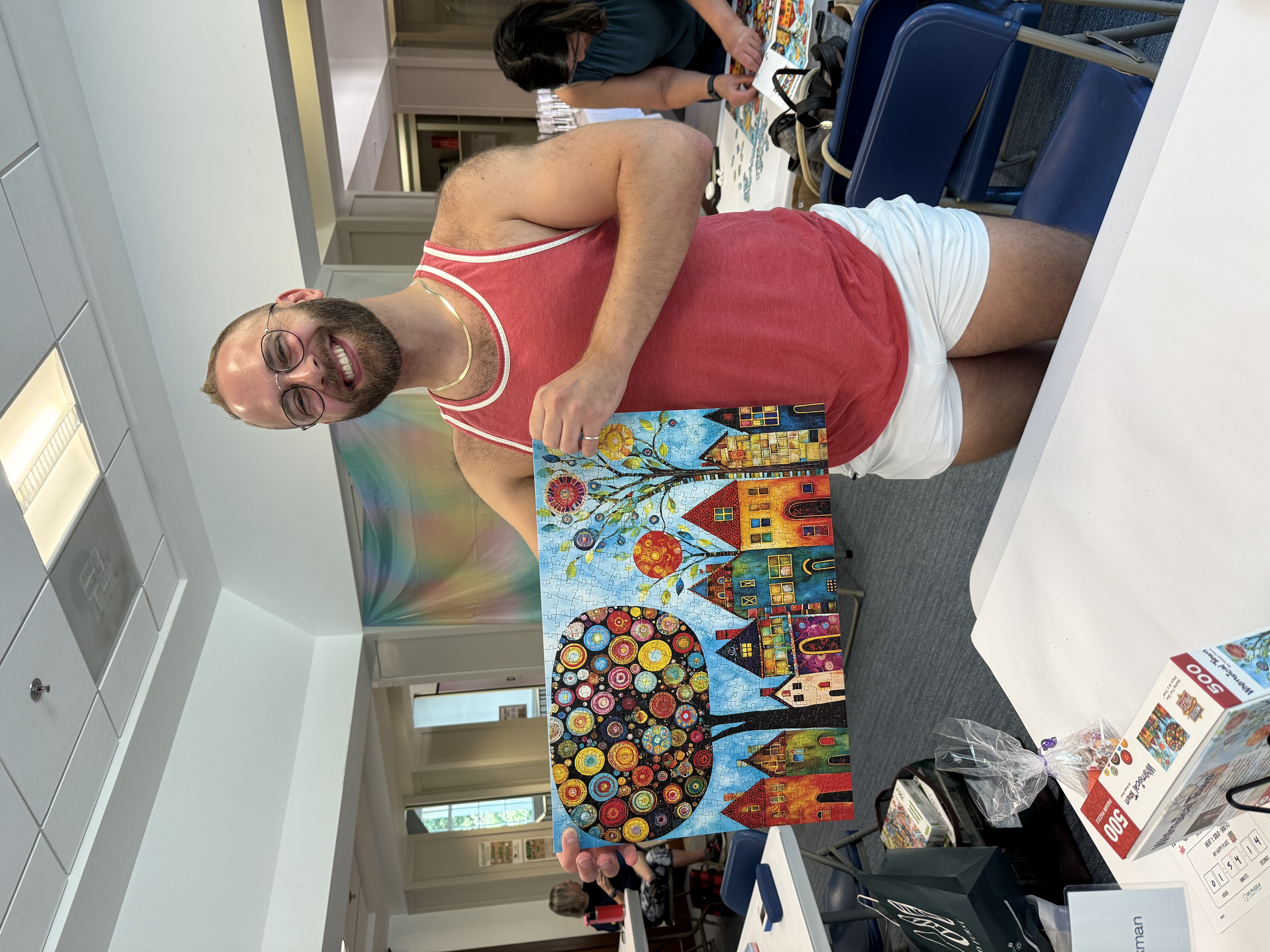 A photo of Andrew holding up my completed puzzle, My Happy Place.