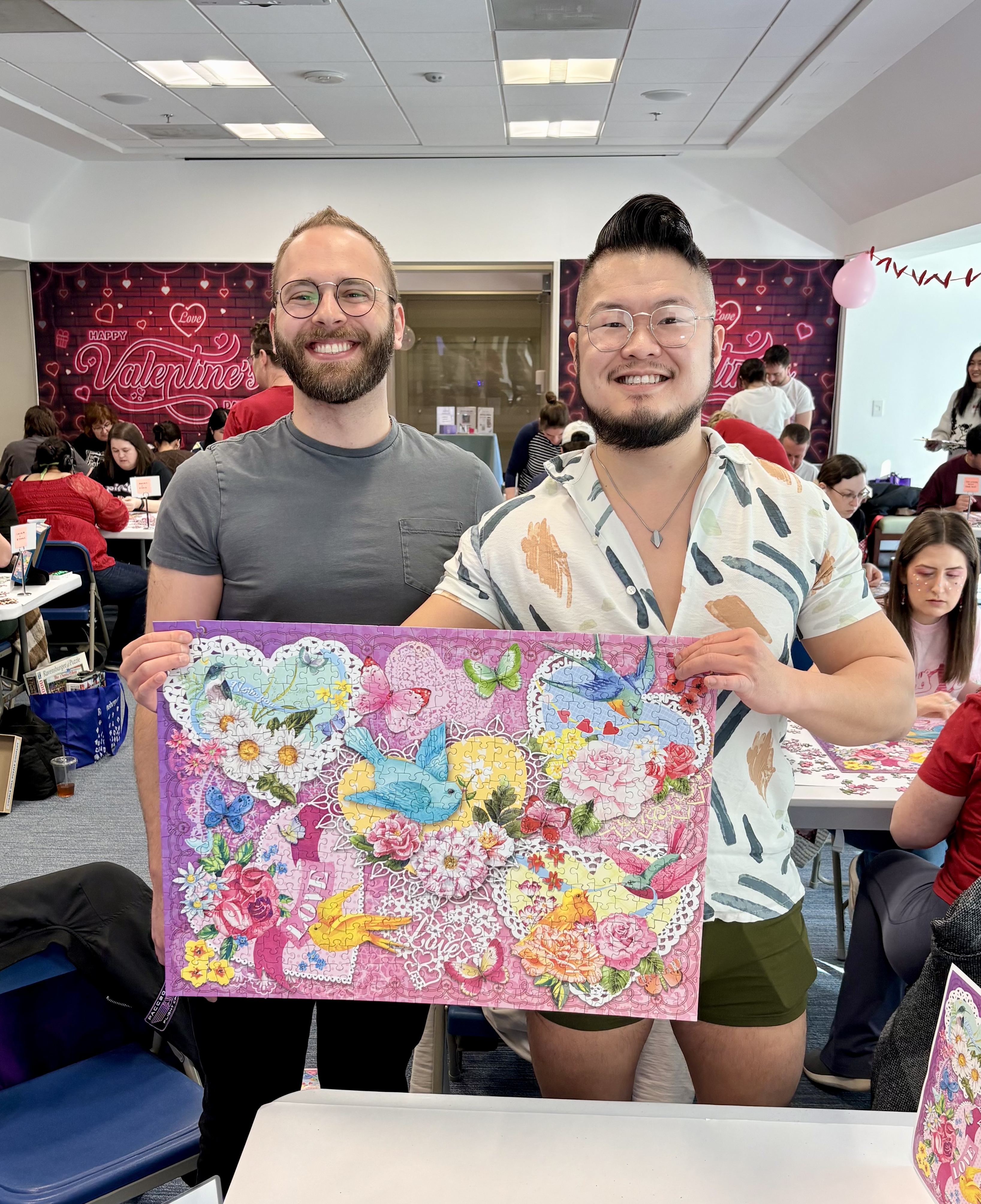A photo of Andrew and Michael holding their completed puzzle, Be Mine.