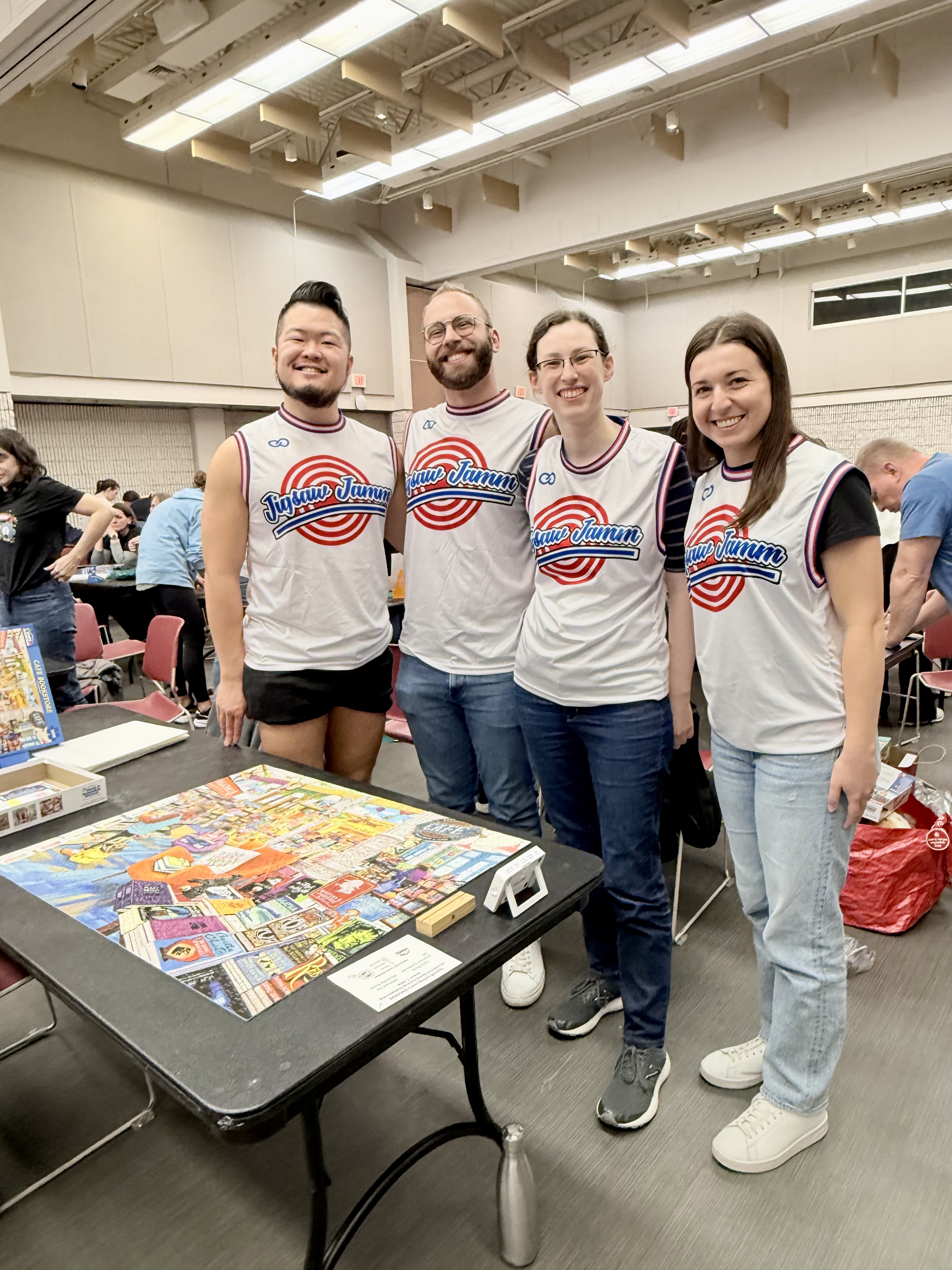 A photo of Jigsaw JAMM standing by their completed puzzle, Cafe Bookstore.